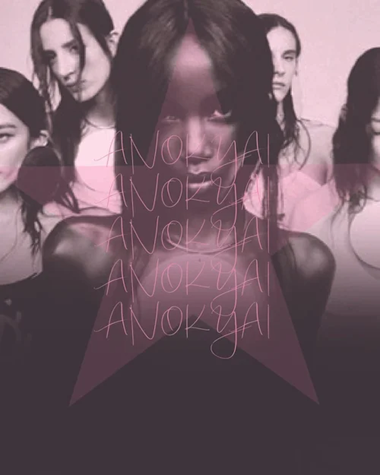 A stylized, multi-layered fashion photograph in muted pink and black tones. At the center is a close-up portrait of model Anok Yai looking directly at the camera, flanked by lighter, blurred images of four other models in the background. A large, semi-transparent star graphic is centered over the composition, containing thin handwritten cursive text reading ANOK YAI repeated five times down the center.